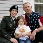 A portrait of retired Command Sergeant Major Gail Ernst, sitting on a porch alongside his then-wife Joni Ernst, who is in her military uniform, and their young daughter Libby.