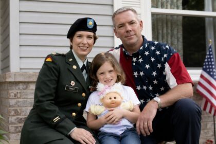 A portrait of retired Command Sergeant Major Gail Ernst, sitting on a porch alongside his then-wife Joni Ernst, who is in her military uniform, and their young daughter Libby.