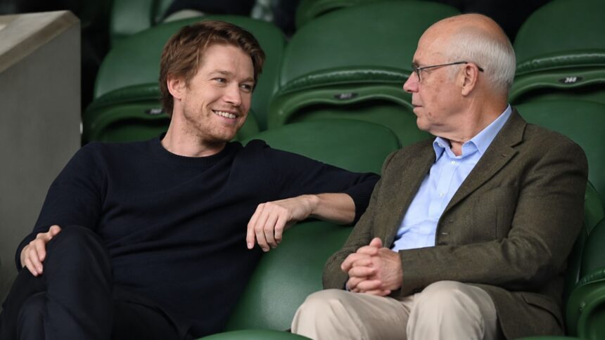 Joe Alwyn in conversation with an older companion at Wimbledon