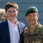 Bear Grylls in military uniform standing next to his middle son Marmaduke Mickey Percy Grylls in a blue blazer.