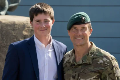 Bear Grylls in military uniform standing next to his middle son Marmaduke Mickey Percy Grylls in a blue blazer.
