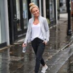 Woman wearing casual sportswear walking along a rain-soaked city street