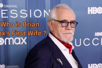 Scottish actor Brian Cox wearing a navy suit and glasses on a red carpet, with text asking "Who is Brian Cox's First Wife?" overlaying the image.