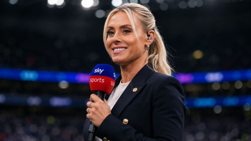 British sports broadcaster Emma Paton holding a Sky Sports microphone, smiling in a dark stadium setting.