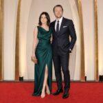 Formally dressed couple posing together on the red carpet at a major film awards ceremony