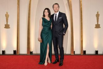 Formally dressed couple posing together on the red carpet at a major film awards ceremony