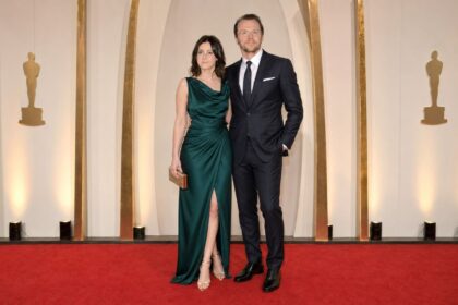 Formally dressed couple posing together on the red carpet at a major film awards ceremony