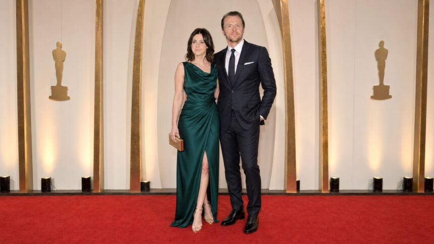 Formally dressed couple posing together on the red carpet at a major film awards ceremony