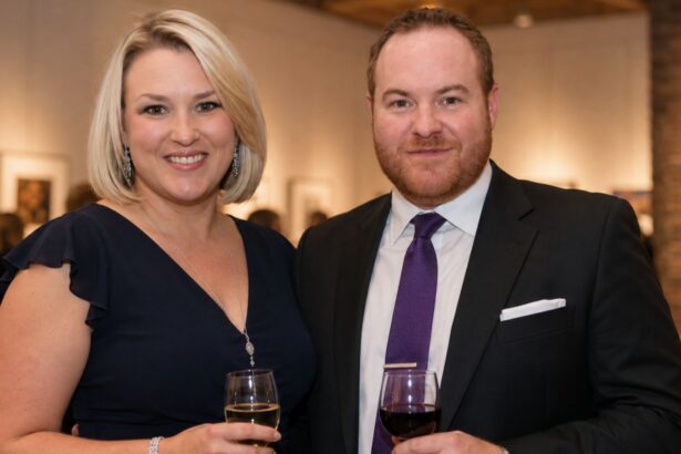 British entrepreneur Sara Davies, wearing a navy blue dress, smiling beside her husband Simon Davies, who is wearing a dark suit and purple tie, at an evening event.