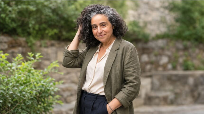 Outdoor editorial portrait of a woman with curly salt-and-pepper hair wearing an olive blazer